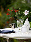 Blumenvase und Teller auf Gartentisch