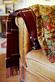 Wolldecke und besticktes Textil hängen an der Armlehne eines Ledersessels