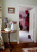 Krug mit Blumen und einem Telefon auf einem Beistelltisch mit Blick durch die offene Tür zum Schlafzimmer