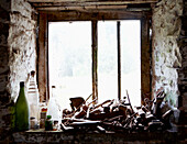 Alte Flaschen und landwirtschaftliche Geräte an einem sonnendurchfluteten Fenster