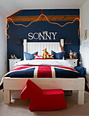 Jungenzimmer mit Union-Jack-Bettwäsche und blau gestrichener Wand mit Love Sonny in weißer Schrift über dem Bett
