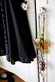 Halsketten und schwarzes Kleid hängen an bemalten Schranktüren