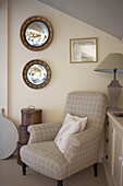 Two convex mirrors and check upholstered armchair in room corner