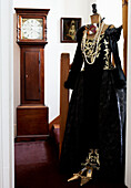 Black stage costume on mannequin with longcase clock on staircase of Grade I listed Elizabethan manor house in Kent 
