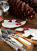 Teaspoons and pinecones with Christmas biscuits on tabletop