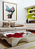 Moderne Kunst im Wohnzimmer mit skulpturalem Metalltisch und Rosenblättern