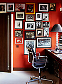 Black leather office chair in red painted study with display portraits