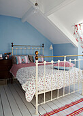 Brass bed with floral cover in attic bedroom of five bedroom Edwardian terraced house