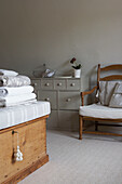 Folded bed covers on blanket box with grey painted storage unit