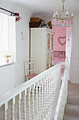 Kleiderschrank mit Glasfront und Kronleuchter im Flur mit offener Tür zum rosa Schlafzimmer