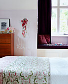 Schneiderpuppe und gesteppte Tagesdecke in einem Schlafzimmer mit Fensterplatz