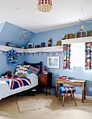 Light blue boy's room with Union Jack bedspread and high wall shelving