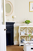 View through doorway to cream living room with original fireplace and shelving