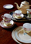 Vintage-Geschirr und dekoratives Porzellan auf einer Tischplatte aus poliertem Holz