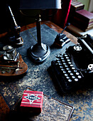 Schreibmaschine auf einem Schreibtisch aus Leder mit Tintenfass und anderen Vintage-Objekten