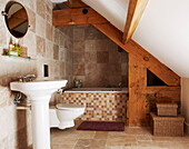 Pedestal basin in tiled bathroom with bath under eaves