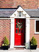 Rote Eingangstür einer Backsteinveranda in einem Landhaus