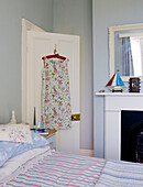 Sommerkleid hängt an der Rückseite der Tür in einem frischen blauen Schlafzimmer