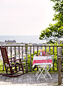 Rocking chair with table on balcony exterior with view to sea