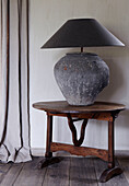 Grey lamp on wooden side table in country home