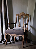 Carved wooden chair with grey curtains in country home
