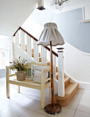 Bench seat and standard lamp with fabric shade in staircase of country home
