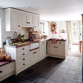 White fitted sunlit kitchen with grey tiled floor