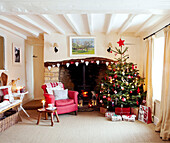 Christmas tree and red armchair at open fireplace with heart shaped decorations