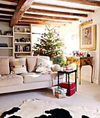 Weihnachtsbaum und Bücherregal mit cremefarbenem Sofa im Balken-Wohnzimmer eines Landhauses