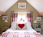 Checked blanket and heart shaped print on cushion on attic bed