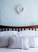 Pastel pink pillow covers on wooden bed with heart shaped ornament