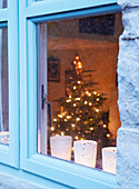 View through rainy window to lit Christmas tree