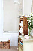 Schnittblumen auf Seitenschrank und Badewanne mit Duscharmatur