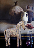 Model horse and glassware in front of artwork