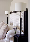 White bedside lamps and upholstered headboard with cut lavender