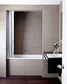 Recessed bathtub and dark wood washbasin in contemporary home