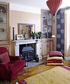 Red velvet armchair at fireplace in living room of City of Bath home Somerset, England, UK