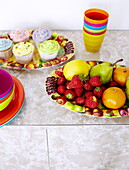 Cupcakes und Früchte auf einer Tischplatte aus Resopal in einem Haus auf der Isle of Wight, England, Vereinigtes Königreich