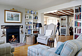 Seating area with bookcases and open fire in Hampshire home England UK