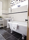 Sockel und freistehende Badewanne im grau gefliesten Badezimmer eines Hauses in Gateshead, Tyne and Wear, England UK