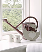 Watering can and milk jugs with duck ornament on windowsill of country house Tunbridge Wells Kent England UK
