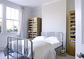 Glass fronted storage cabinets with metal bed in London family home UK