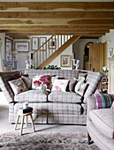 Kariertes Sofa mit geblümten Kissen im offenen Balkenraum des Landhauses Hexham in Northumberland England UK