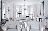 Grand piano and matching white armchairs with a collection of vases London home UK