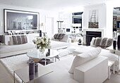 Runder Couchtisch und moderne Kunst in der Sitzecke eines weiß verspiegelten Wohnzimmers in einem Londoner Haus UK
