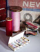 Rosa und rotes Garn auf alten Spulen mit Stoffmustern im Haus einer Londoner Textildesignerin UK