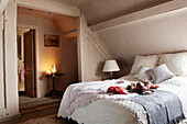 Woollen blankets and cushions on attic bed with view to candlelit side table in festive Oxfordshire home, England, UK