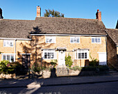 Sunlit terraced stone cottage facade in Oxfordshire, England, UK
