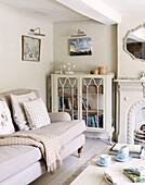 Glass fronted cabinet and sofa in living room of Oxfordshire home, England, UK