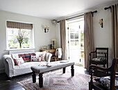 Upholstered footstool and dining chairs with sofa in living room of Oxfordshire home, England, UK